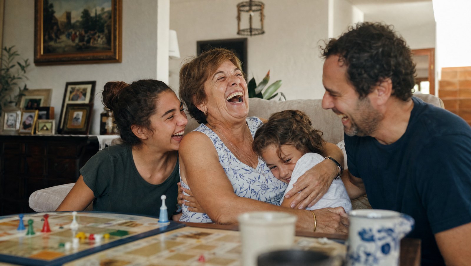 Abuela riéndose a carcajadas en el sofá con su nieto, su hijo y su nieta
