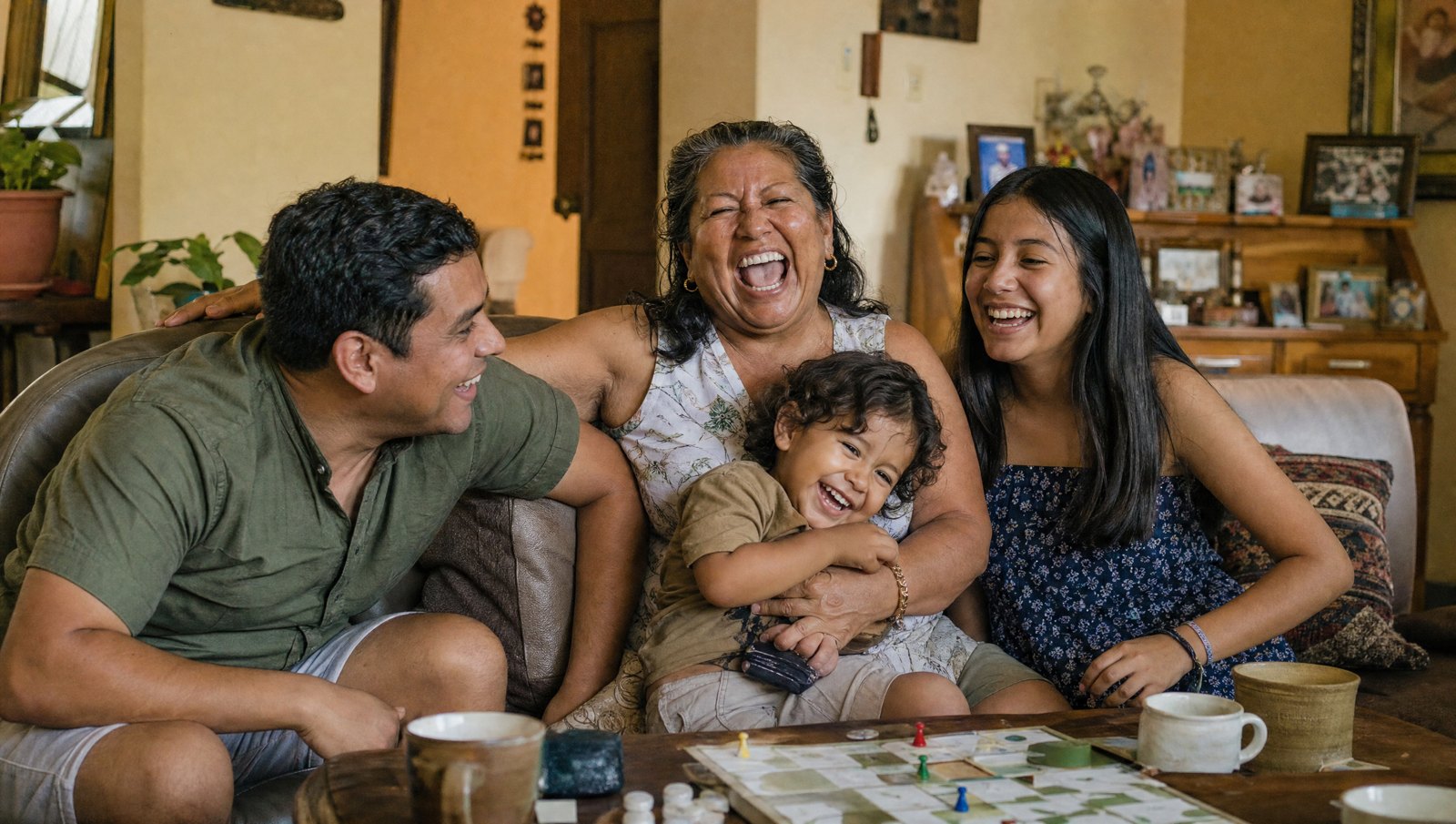 Abuela riéndose a carcajadas en el sofá con su nieto, su hijo y su nieta