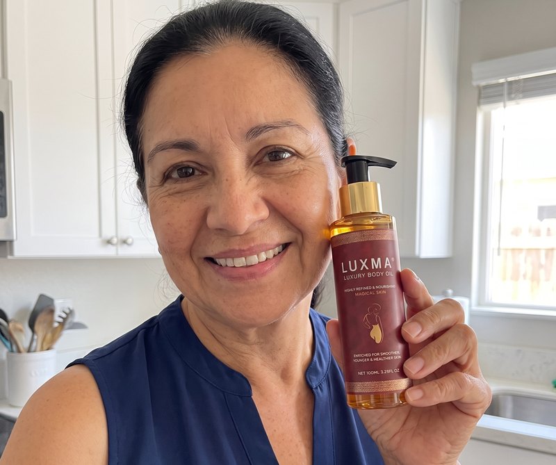 Mujer de unos 61 años con el aceite LUXMA junto a la cara, en su cocina